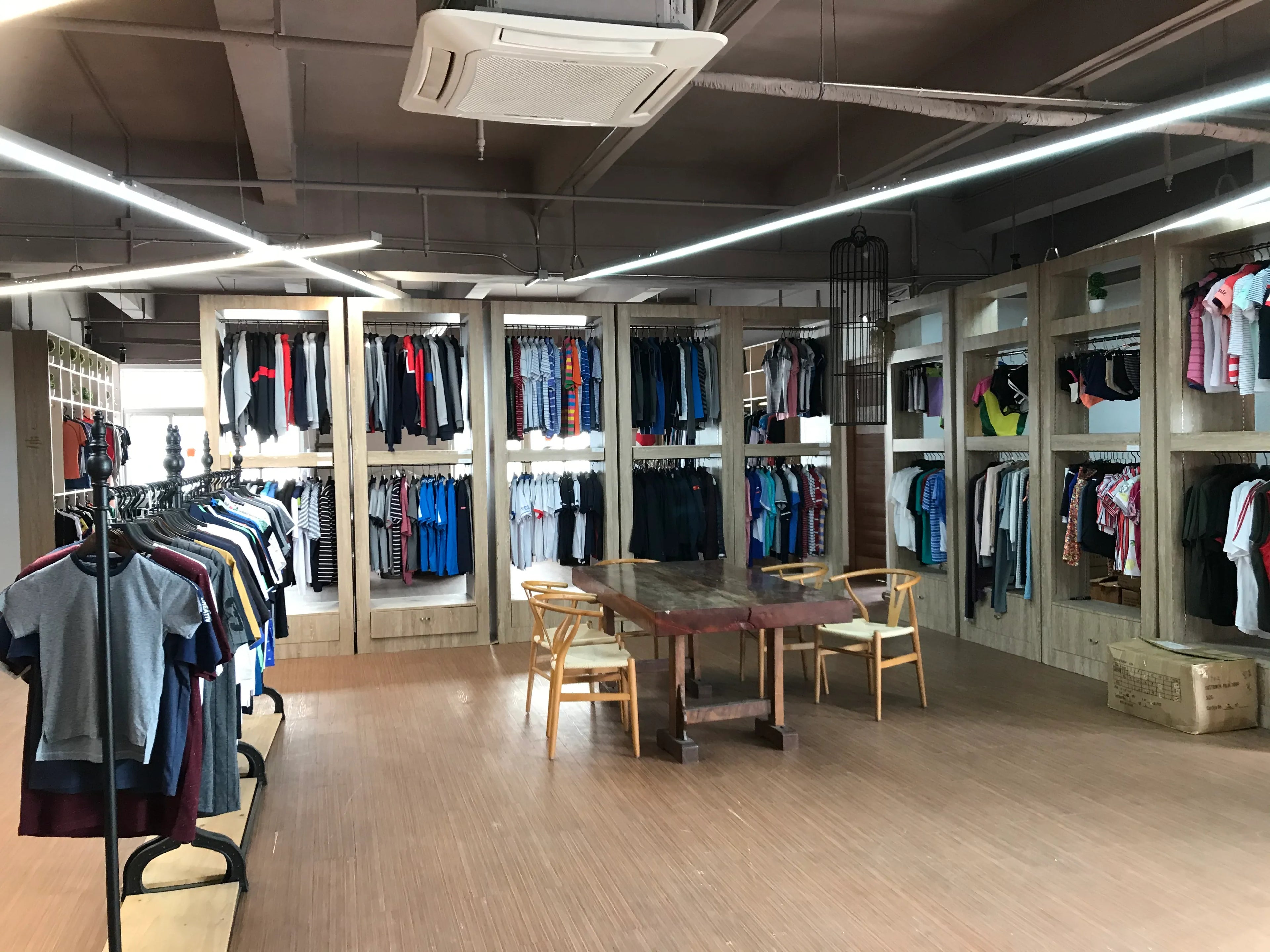 The clothing factory showroom displays a variety of clothing samples, including polo shirts, sweatshirts, shirts, trousers, shorts, skirts, jackets, suit jackets, etc