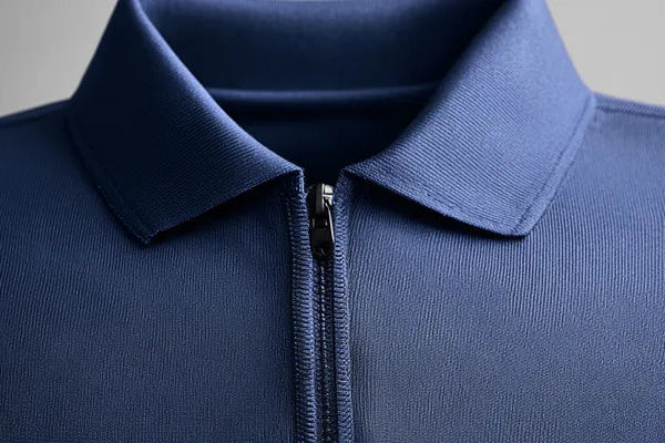 Close-up of a blue zip-up polo shirt on a gray background, example of mid-layer garment