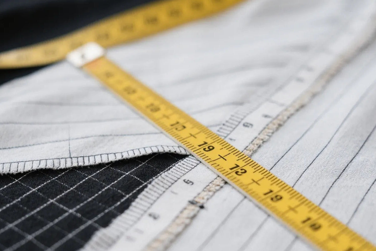 Close-up of a measuring tape on fabric with a ruler, symbolize all samples follow client tech pack strictly, revision support included.